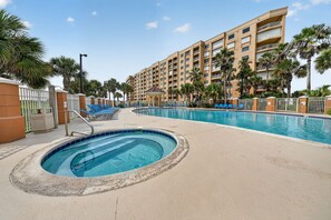 A hotel pool area with multiple swimming pools, lounge chairs, and palm trees. - Oceanfront Condo in Palm Coast Surf Club #317 (Palm Coast)