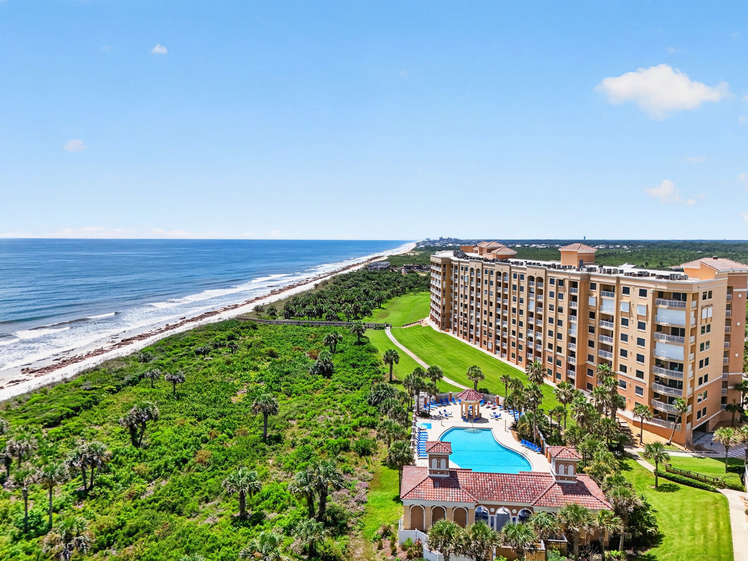 A resort with a pool, beachfront, and a large building with multiple floors.