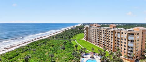 A resort with a pool, beachfront, and a large building with multiple floors.
