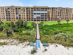 A multi-story hotel with a central courtyard, surrounded by lush greenery and palm trees. - Oceanfront Condo in Palm Coast Surf Club #317 (Palm Coast)