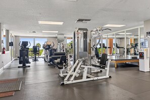 A gym with various exercise equipment, large windows, and a view of the outdoors. - Oceanfront Condo in Palm Coast Surf Club #317 (Palm Coast)