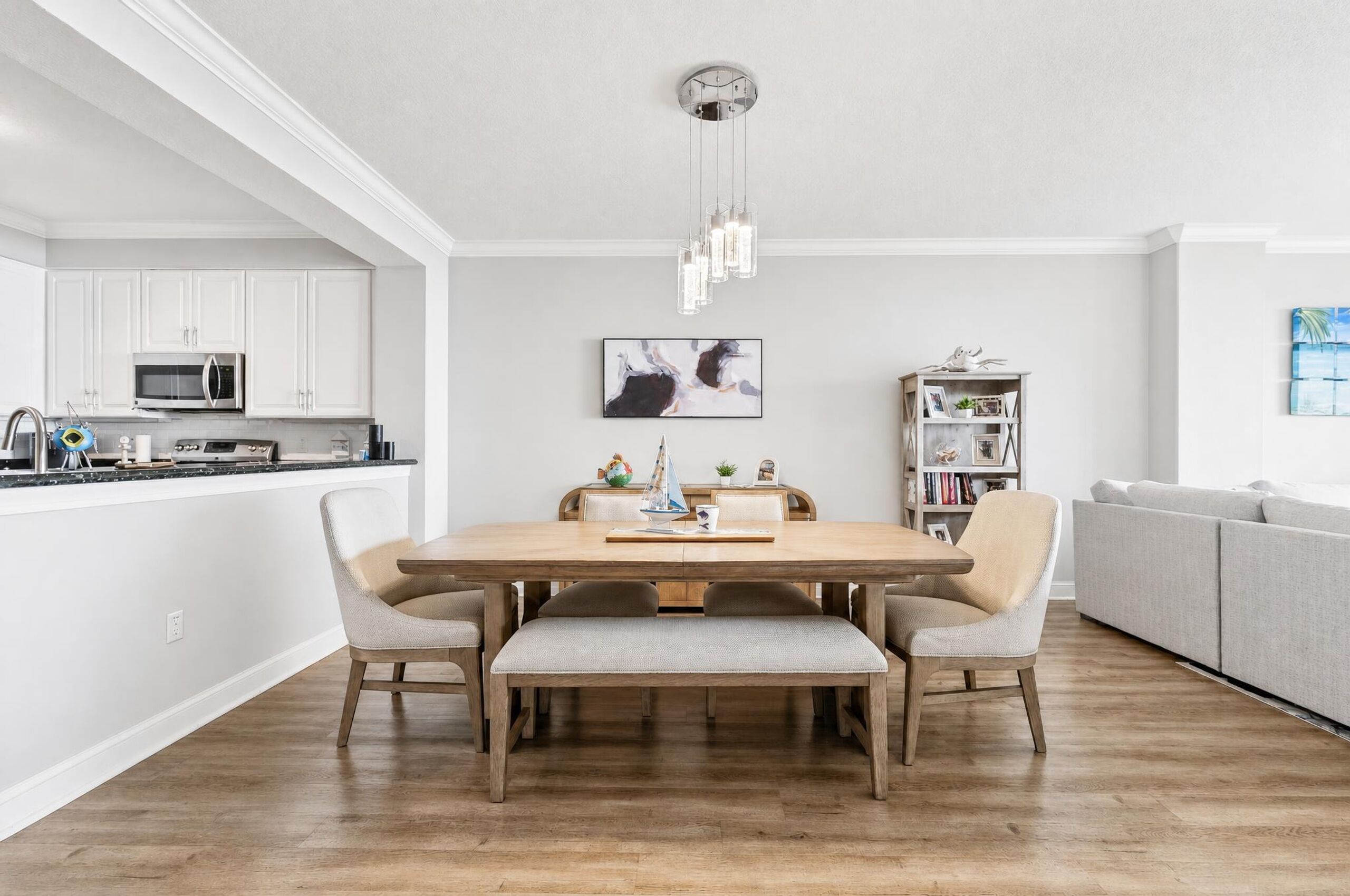 A modern kitchen with white cabinets, a microwave, and a dining area with a wooden table and chairs.