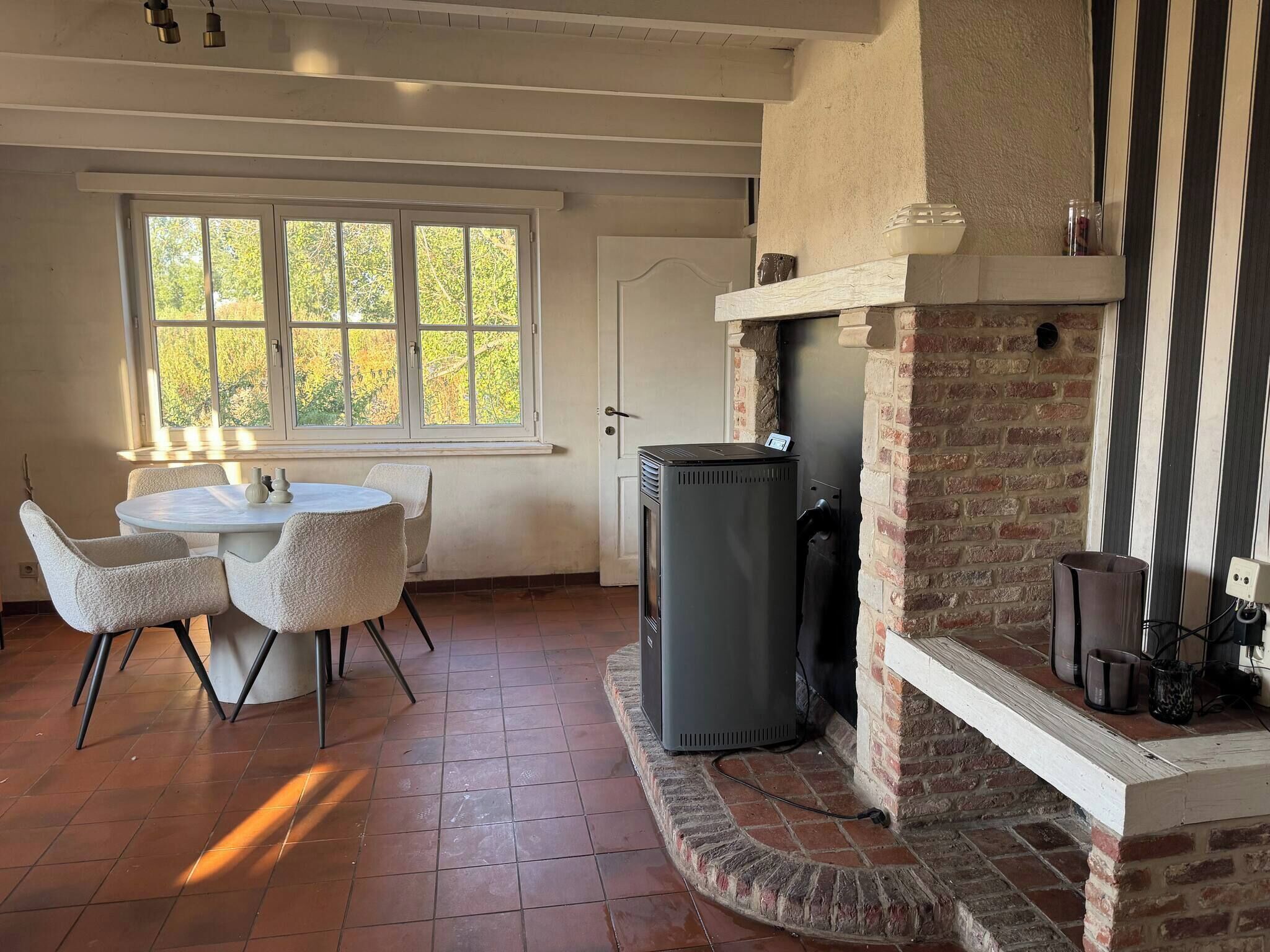 Una habitación con chimenea, una mesa de comedor con sillas y una ventana con vista a árboles.