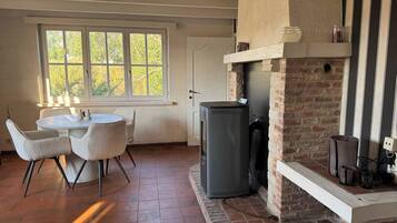 Una habitación con chimenea, una mesa de comedor con sillas y una ventana con vista a árboles.