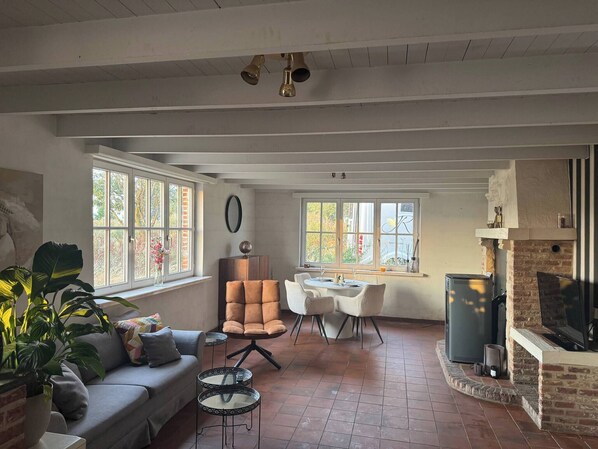 Un salón amplio con chimenea, comedor y ventanas grandes.