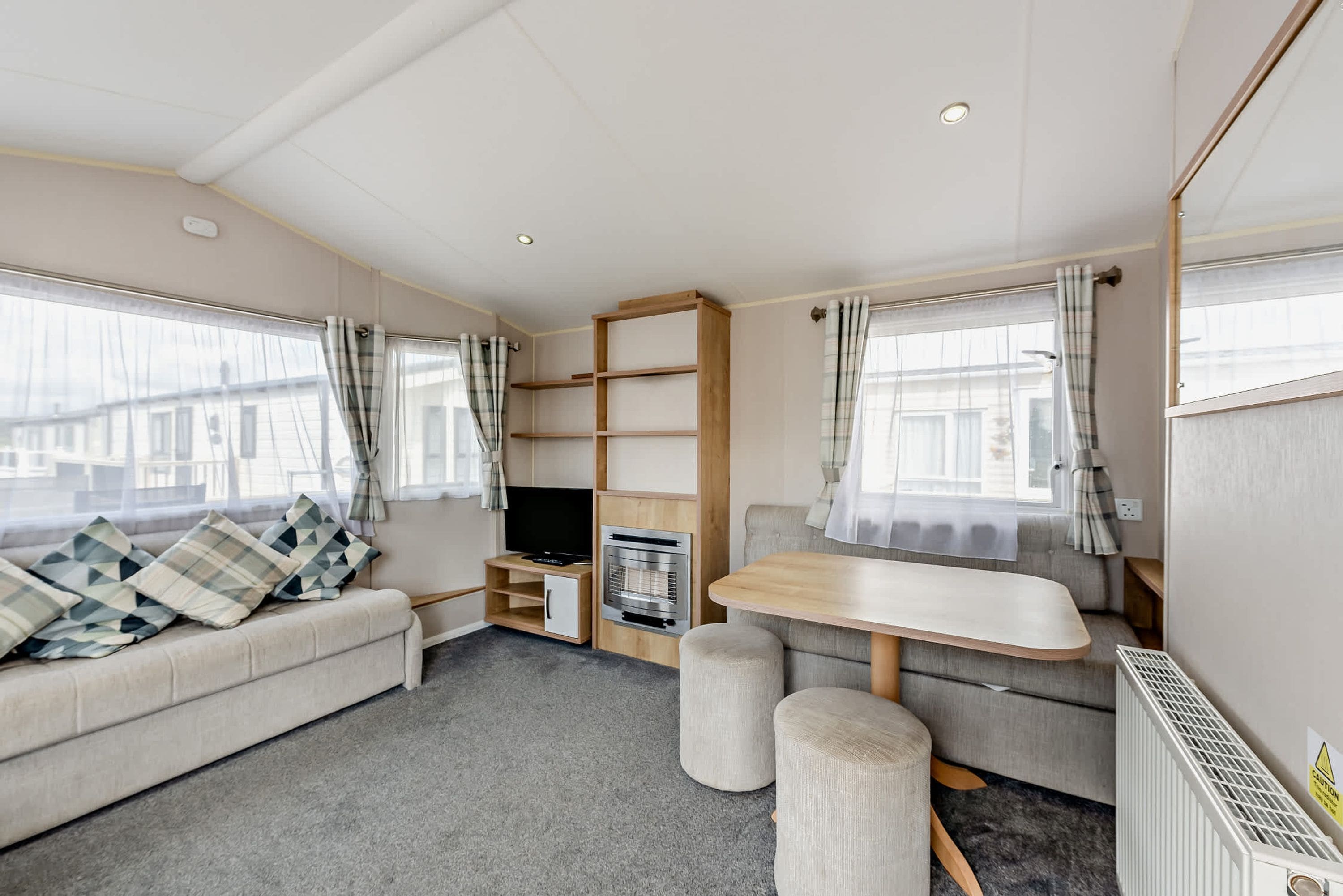 Ein gemütliches Wohnmobil-Interieur mit einer Sitzecke, einem Fernseher, einem kleinen Tisch und einer Küchenzeile.