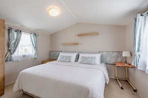 A bedroom with a bed, bedside tables, a lamp, and curtains. - Host Stay - Meadow View (Winchelsea)
