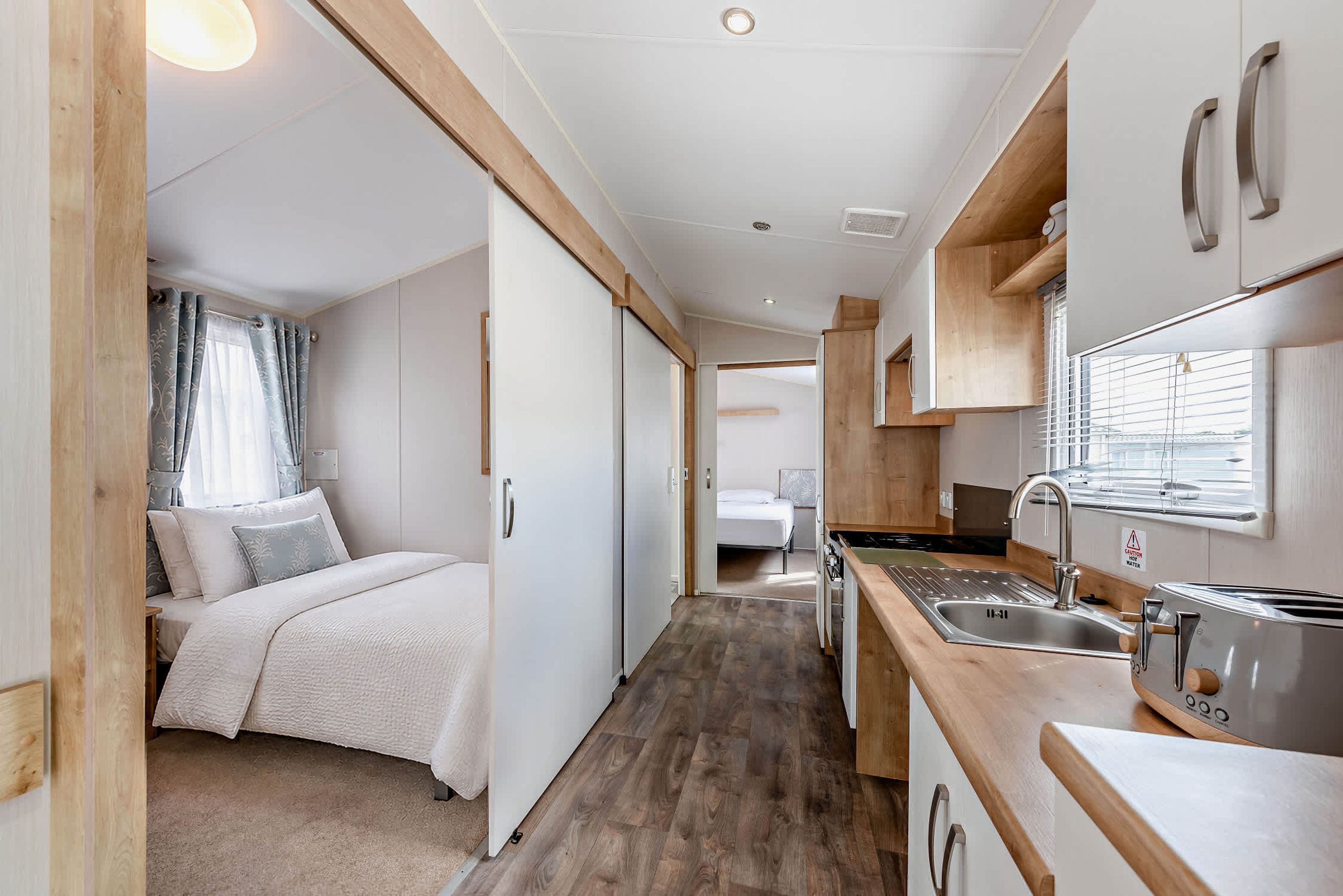 Interior compacto de una autocaravana con kitchenette, zona de descanso con cama y baño.