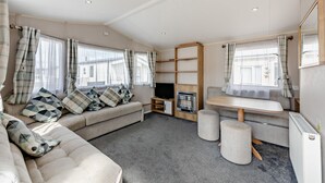 Ein modernes Wohnzimmer mit einer Couch, einem Fernseher, einem Kamin und einem Essbereich.