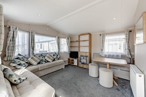 A modern living room with a sofa, a TV, a fireplace, and a dining area. - Host Stay - Meadow View (Winchelsea)