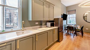 A modern kitchen with a large window, a built-in microwave, and a dining area with a table and chairs. - Host Stay - The Georgian Quarter at Catharine I (Liverpool)