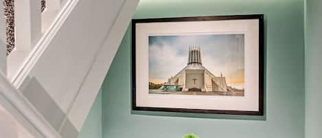 A framed picture of a church on a wall with a small potted plant below it.