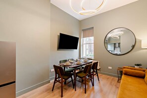 A dining area with a table set for four, a television mounted on the wall, and a large mirror. - Host Stay - The Georgian Quarter at Catharine I (Liverpool)