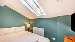 A bedroom with a skylight, a bed, a nightstand with a lamp, a radiator, and a wooden nightstand. - Host Stay - The Georgian Quarter at Catharine I (Liverpool)