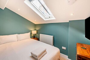 A bedroom with a skylight, a bed, a nightstand with a lamp, a radiator, and a wooden nightstand. - Host Stay - The Georgian Quarter at Catharine I (Liverpool)