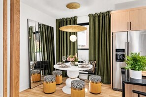Una cocina moderna con refrigerador empotrado, armarios de madera y un comedor con una mesa redonda y sillas a juego.