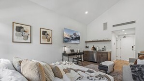 A modern bedroom with a bed, a desk, and a mounted TV. - Luxury Penthouse Studio | Ski-In/Ski-Out | Canyons Village Park City (Park City)