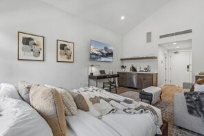 A modern bedroom with a bed, a desk, and a mounted TV. - Luxury Penthouse Studio | Ski-In/Ski-Out | Canyons Village Park City (Park City)