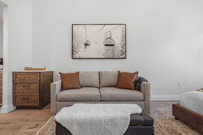 A modern living room with a sofa, a coffee table, a wooden cabinet, and a framed picture on the wall. - Luxury Penthouse Studio | Ski-In/Ski-Out | Canyons Village Park City (Park City)