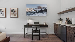 A modern kitchen with a wooden countertop, a built-in dishwasher, and a dining area with a dark wooden table and chair. - Luxury Penthouse Studio | Ski-In/Ski-Out | Canyons Village Park City (Park City)