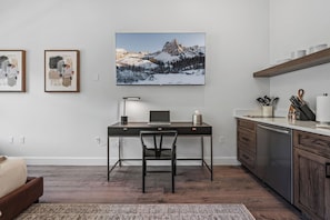 A modern kitchen with a wooden countertop, a built-in dishwasher, and a dining area with a dark wooden table and chair. - Luxury Penthouse Studio | Ski-In/Ski-Out | Canyons Village Park City (Park City)