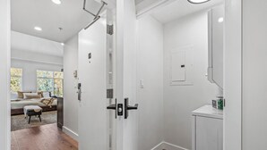 A modern interior with a wooden floor, a bed with a view, a bathroom with a mirror and a sink, and a door with a handle. - Luxury Penthouse Studio | Ski-In/Ski-Out | Canyons Village Park City (Park City)