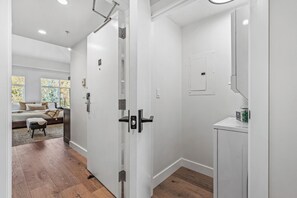 A modern interior with a wooden floor, a bed with a view, a bathroom with a mirror and a sink, and a door with a handle. - Luxury Penthouse Studio | Ski-In/Ski-Out | Canyons Village Park City (Park City)