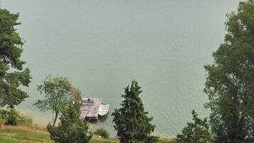 Un lac avec un quai et un petit bâtiment, le tout entouré d’une forêt dense.