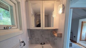 Un baño con lavamanos blanco, dos armarios, un espejo y una ventana.