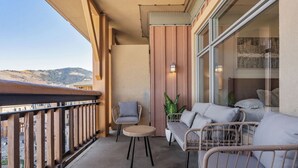 Ein Balkon mit Korbmöbeln, einem kleinen Tisch und einem Blumentopf.