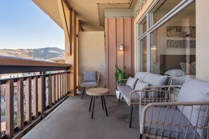Ein Balkon mit Korbmöbeln, einem kleinen Tisch und einem Blumentopf.