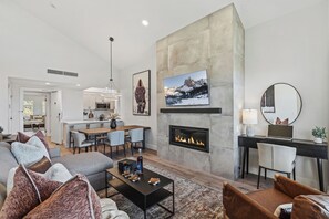 Ein modernes Wohnzimmer mit Kamin, Essbereich und einer Küche im Hintergrund.