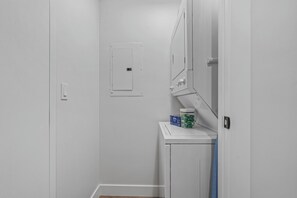 A white utility room with a door, a small electrical panel, and a counter with a jar and a box. - Luxury, Renovated 2BR Penthouse | Ski-In/Ski-Out | Canyons Village Park City (Park City)