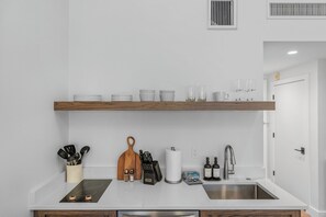 A modern kitchen with a white countertop, stainless steel sink, and wooden shelves above. - Luxury, Renovated 2BR Penthouse | Ski-In/Ski-Out | Canyons Village Park City (Park City)