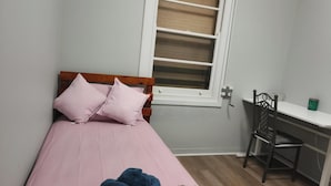 A bedroom with a bed, a desk, and a chair.