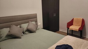 A bedroom with a bed, a wardrobe, and a chair.