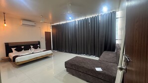 Un dormitorio con cama, sofá, ventilador de techo y ventana con cortinas.