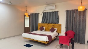 Un dormitorio con una cama de madera, cortinas grises, una silla roja y un equipo de aire acondicionado en la pared.