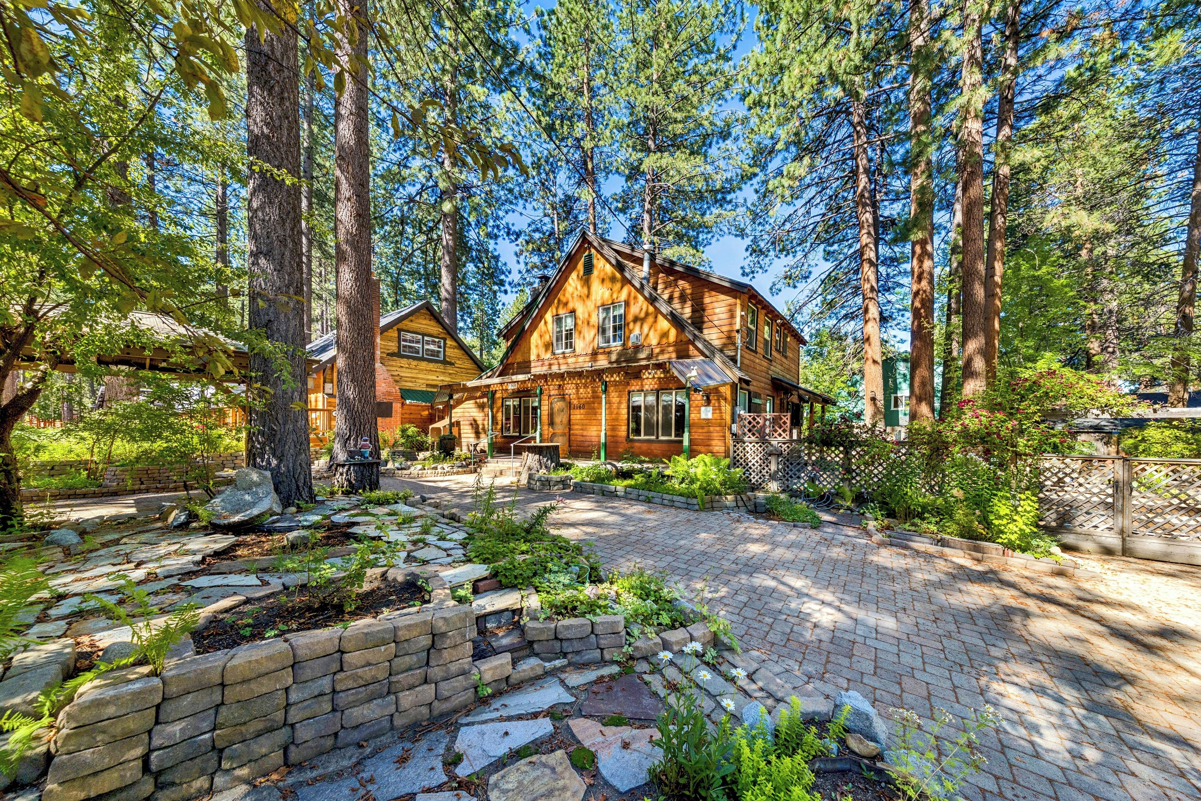 A wooden cabin with a stone pathway leading to the entrance, surrounded by tall trees.