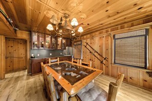 Un interior de madera con una mesa de comedor, armarios y un ventanal con persianas.