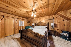 A wooden-paneled room with a bed, a nightstand, a lamp, and a heater. - 3BR Tahoe Hideaway with Mountain Views and Rustic Feels (South Lake Tahoe)