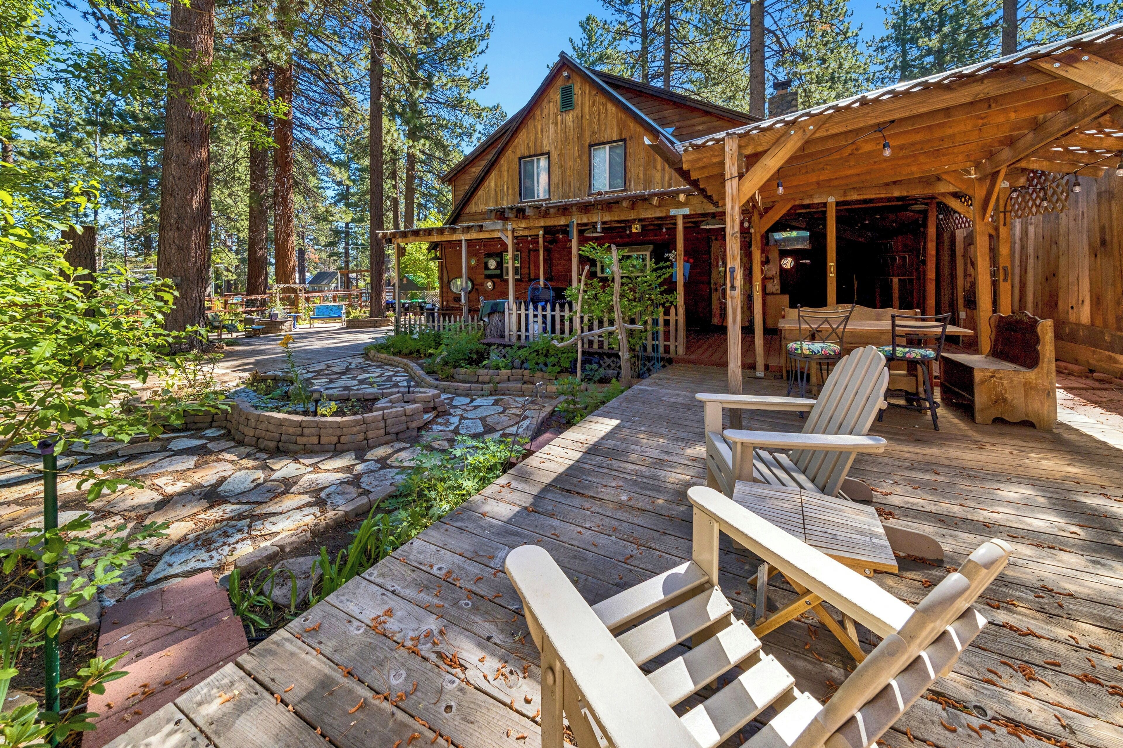 A wooden cabin with a deck, outdoor seating, and a fire pit.