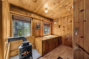 Ein Holzinterieur mit Kamin, großen Fenstern und Blick ins Freie.
