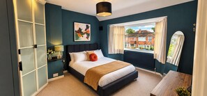 A bedroom with a bed, a window with curtains, a radiator, and a view of houses outside. - 3-bed Hot Tub Pool Table Off-road Parking Sleeps 5 (Birmingham)
