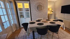 Un comedor con una mesa, sillas, un espejo, un televisor y un radiador.