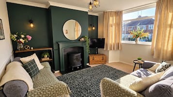 A living room with a fireplace, a television, and a window with curtains.