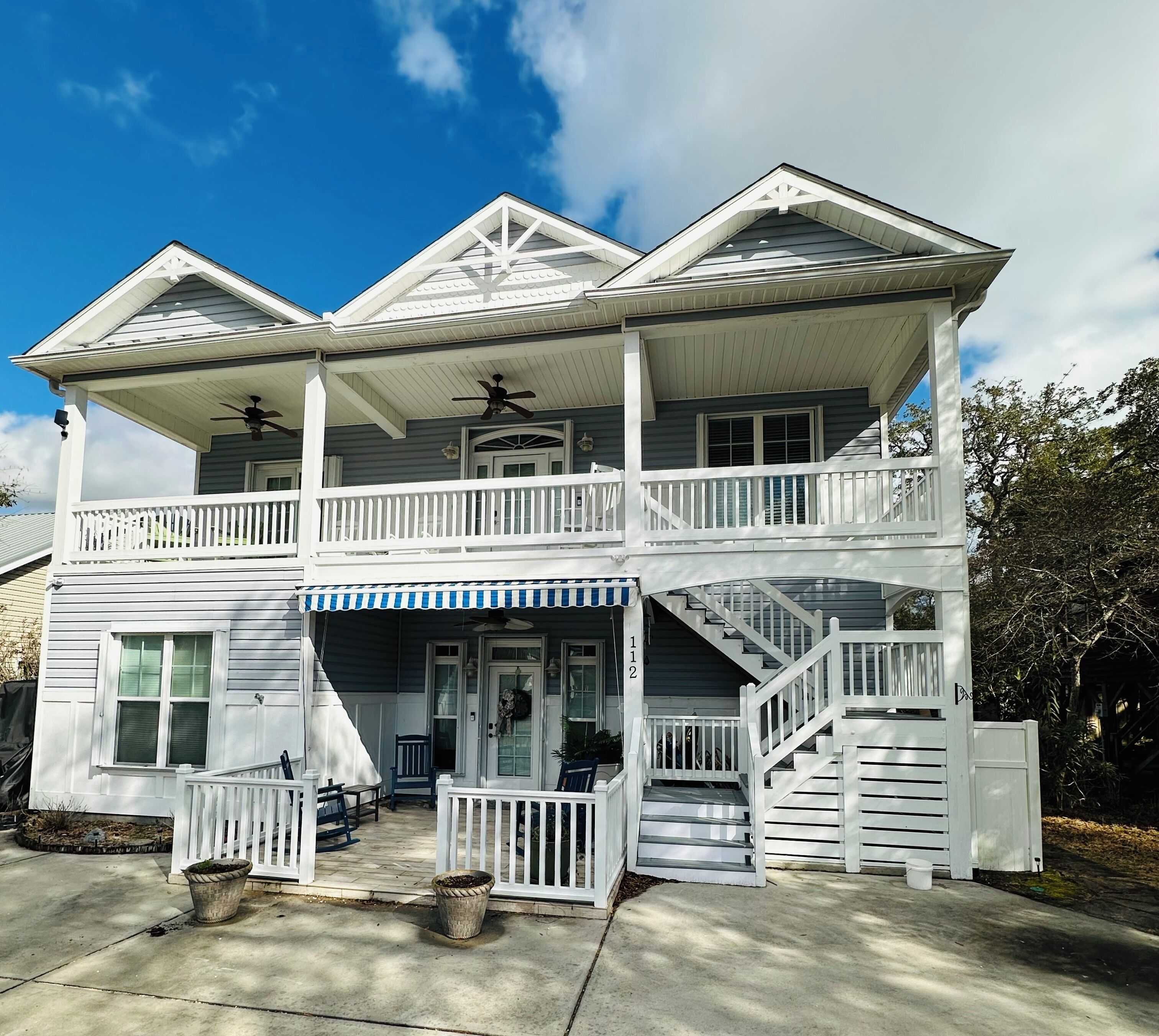 A two-story house with a balcony, a porch, and a staircase leading to the upper level.