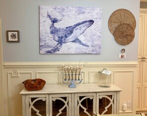 A room with a white cabinet, a decorative wall hanging, and a framed picture. - Brisas del Mar- a West End Retreat, 6 BR, Dual Living spaces, 6 Seater Golf Cart (Oak Island)