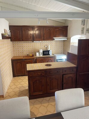 A compact kitchen with wooden cabinets, a microwave, a toaster, and a refrigerator. - Large Studio Apartment in Lunghignano (Montegrosso)