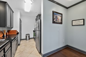 A kitchen with stainless steel appliances, a wooden countertop, and a trash can. - Tusk & Tide | Near the Stadium & Campus! (Tuscaloosa)